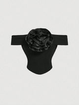 Black off-shoulder top with a large flower detail on a light gray background