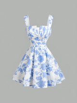 A sleeveless white dress with a blue floral toile pattern, featuring a sweetheart neckline, structured bodice, and a flared skirt, shown against a solid gray background.