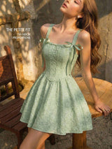 Woman wearing a green dress sitting outdoors on a wooden bench.