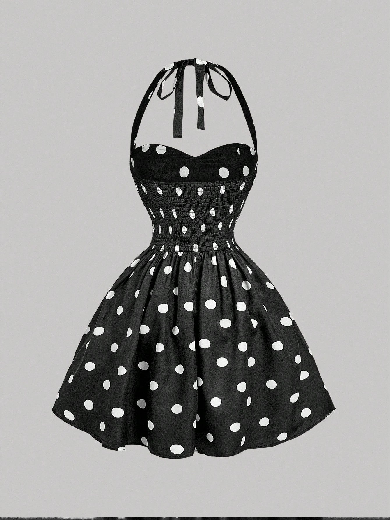 Black dress with white polka dots on a gray background
