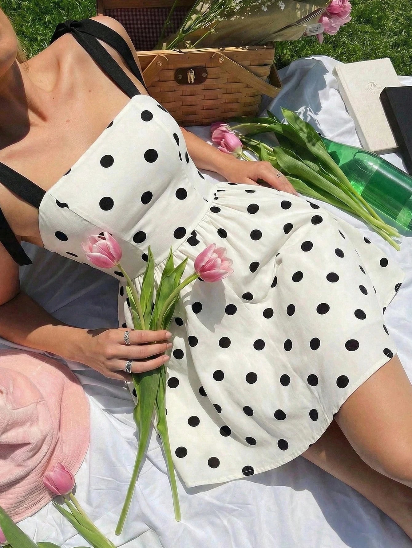 Woman in a polka dot dress holding flowers on a picnic blanket