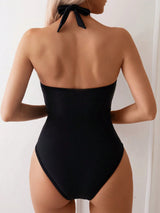 Black halter neck swimsuit worn by a model against a white background