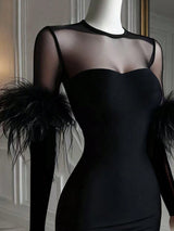 Black dress with sheer sleeves and feather details on a mannequin against a neutral background