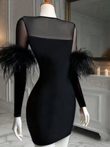 Black dress with feather details on a mannequin against a decorative wall.