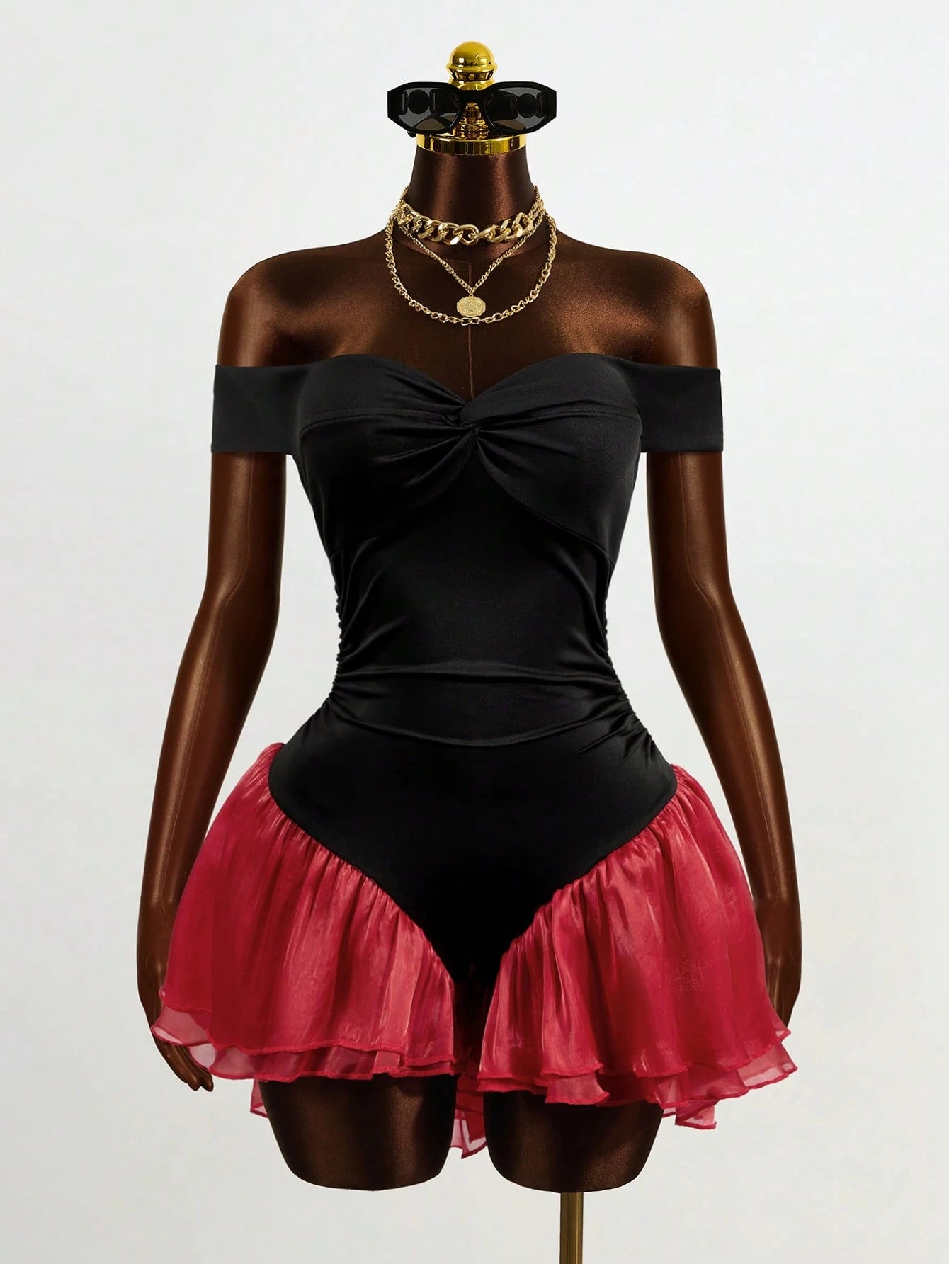 Mannequin wearing a black off-shoulder top with a red skirt on a white background