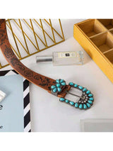 Belt with turquoise buckle on a white surface with decorative elements