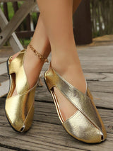 Gold shoes worn on feet standing on a wooden floor.