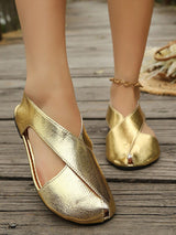 Gold flat shoes worn on a wooden floor