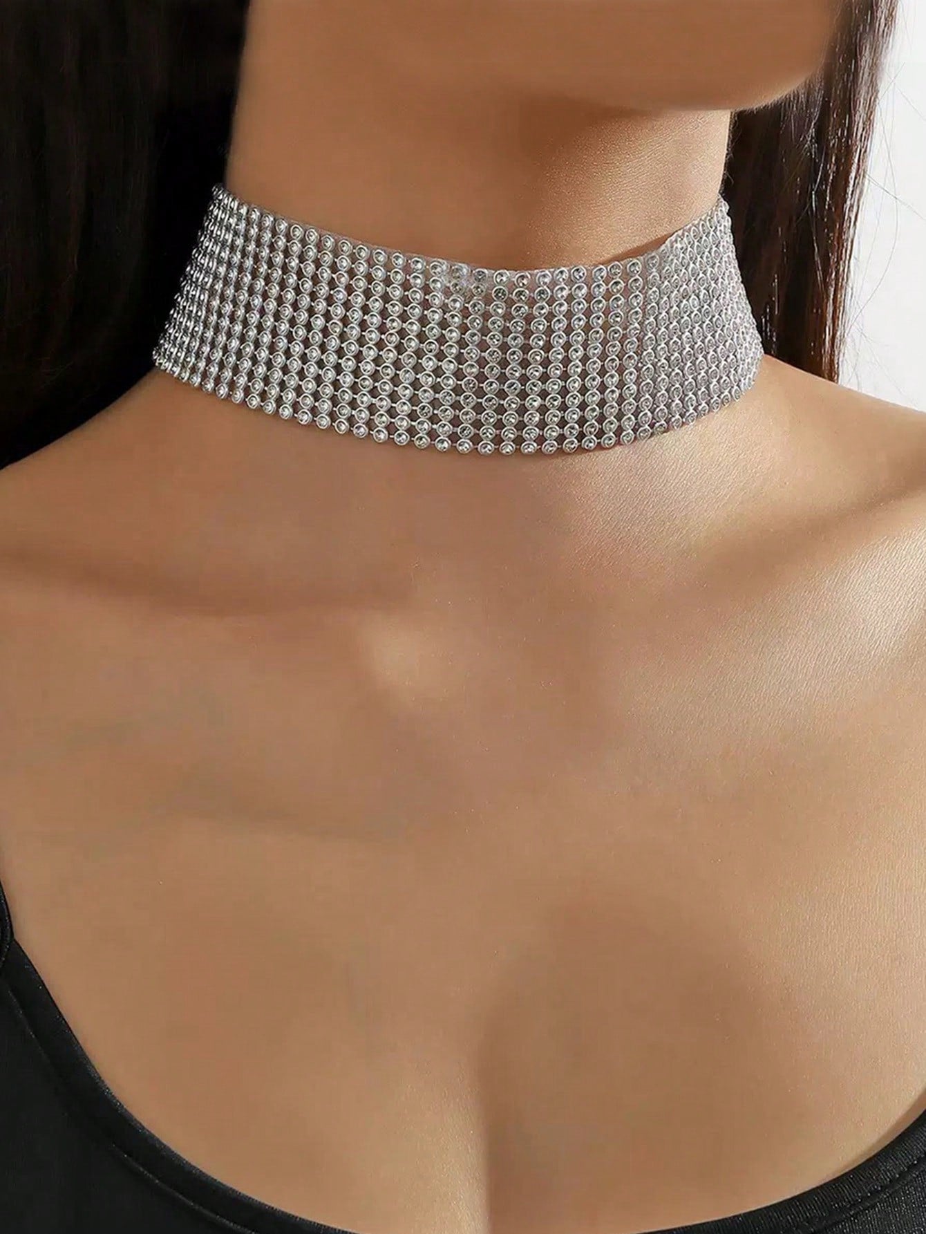 Silver choker necklace worn by a person against a neutral background