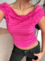 Person wearing a bright pink textured top and black pants indoors.