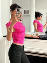 Person wearing a pink top and black pants taking a mirror selfie.