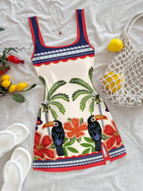 Colorful dress with toucan and floral design on a white surface with accessories.