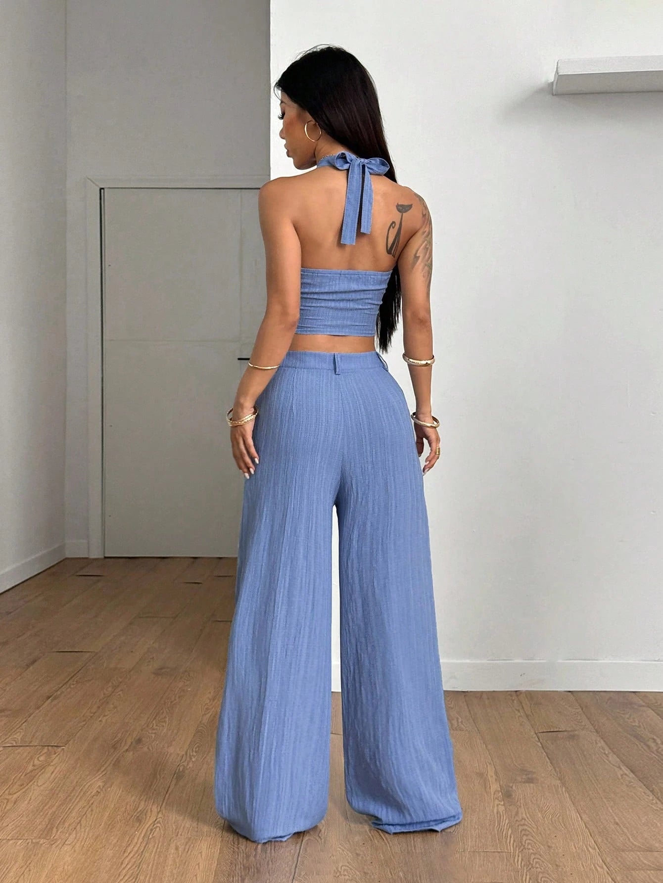 Woman wearing a blue outfit with wide-leg pants in a minimal indoor setting