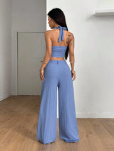 Woman wearing a blue outfit with wide-leg pants in a minimal indoor setting