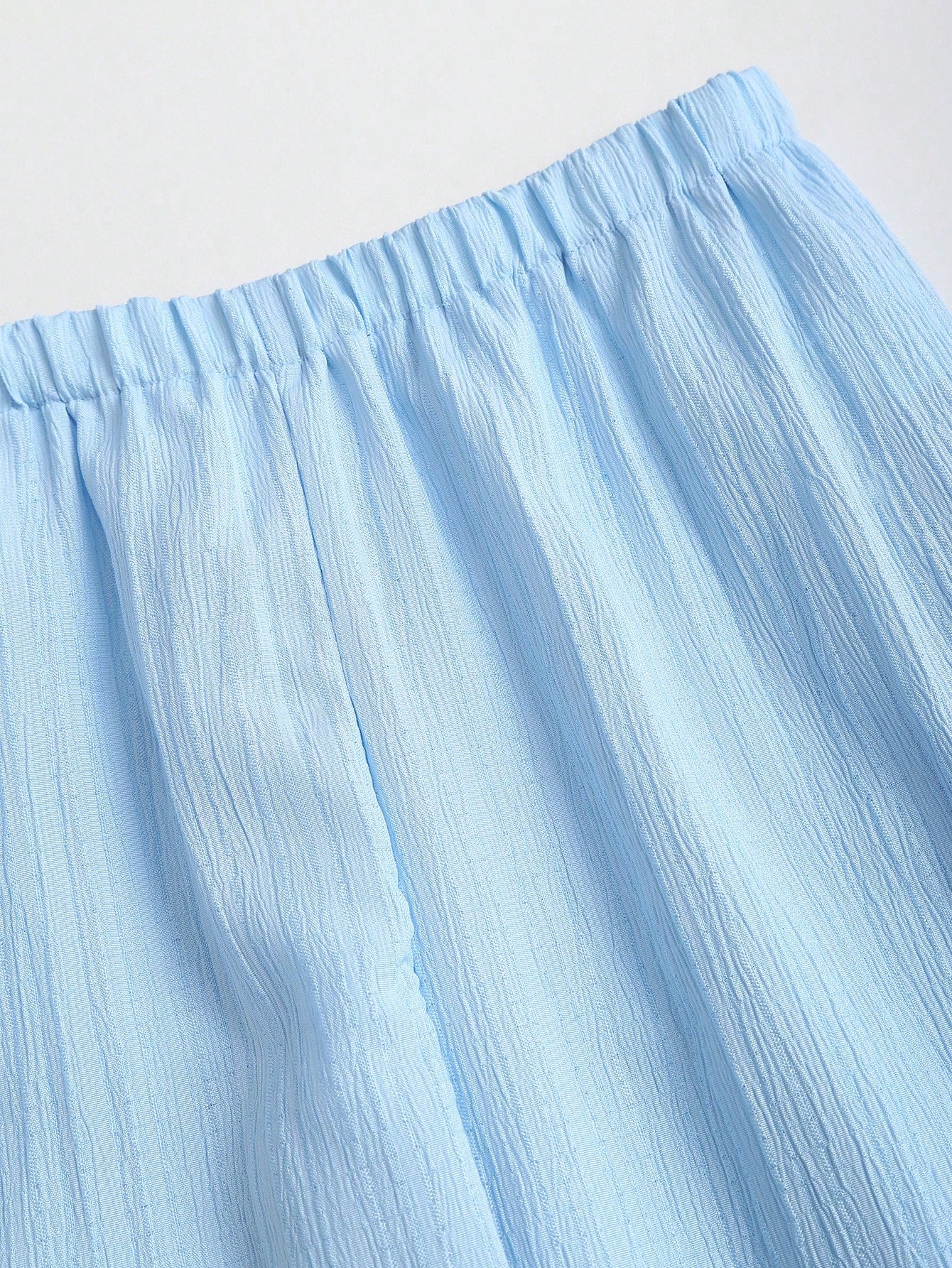 Close-up of a light blue skirt with a plain background