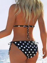 Person wearing a black and white polka dot bikini on a beach.