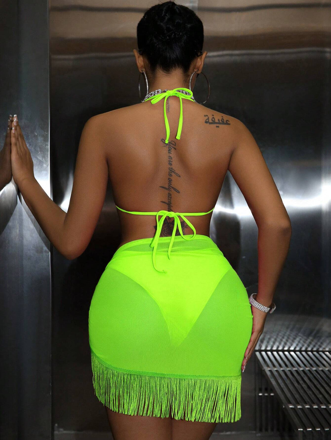 Person wearing a neon green fringe dress with a metallic background
