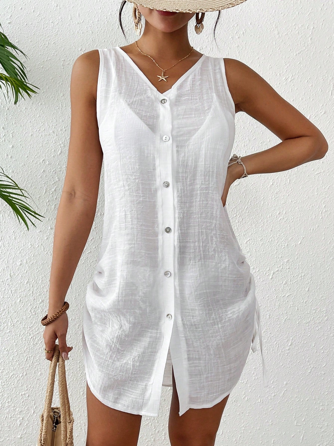 Woman wearing a white sleeveless button-up shirt against a white background
