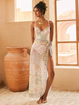 Woman wearing a floral dress standing in a sunlit room with large windows and a terracotta pot.