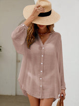 Woman wearing a light pink button-up shirt and straw hat indoors.