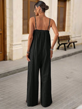 Woman wearing a black jumpsuit standing on a street with a building in the background