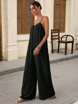 Woman wearing a black jumpsuit standing on a street with a building in the background