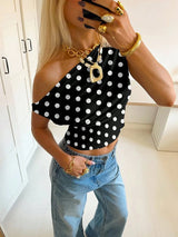 Person wearing a black polka dot top and blue jeans indoors.