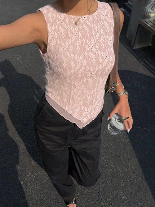 Person wearing a light pink lace top and black pants, holding a water bottle on a dark surface.