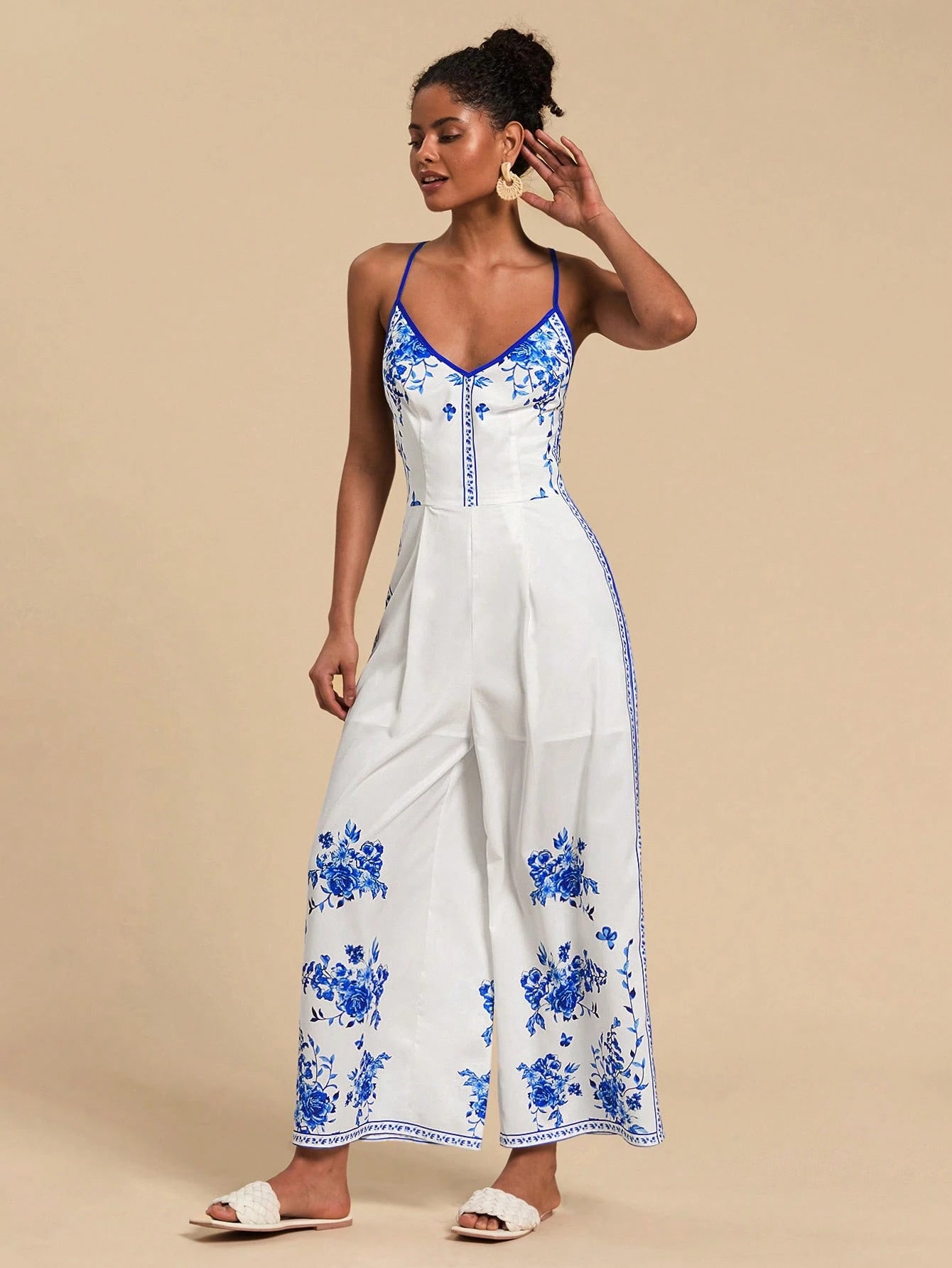 Woman wearing a white dress with blue floral patterns on a beige background