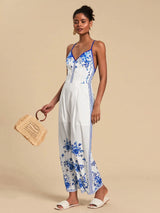 Woman wearing a white dress with blue floral patterns, holding a woven bag on a beige background