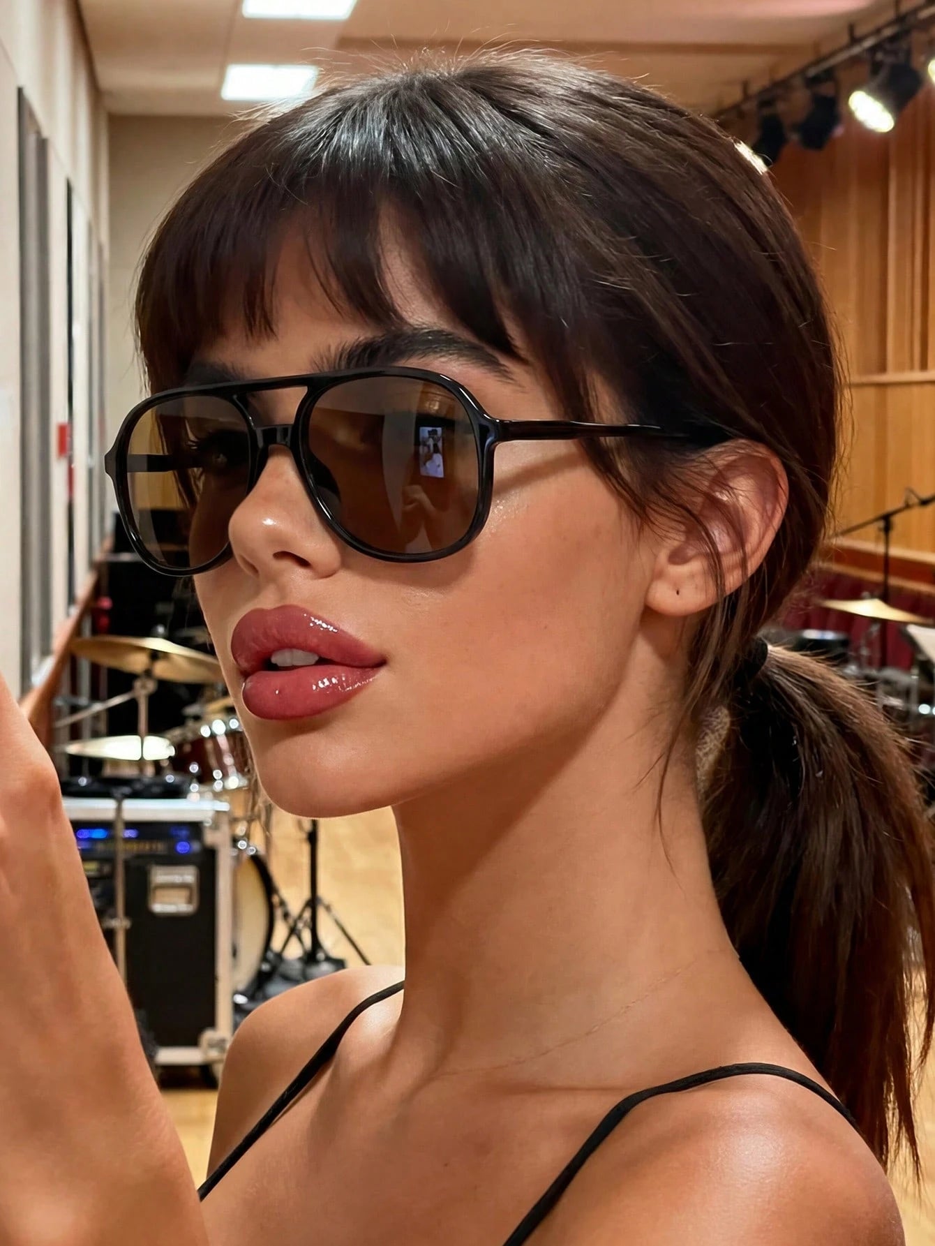 Woman wearing sunglasses with a blurred background of musical equipment