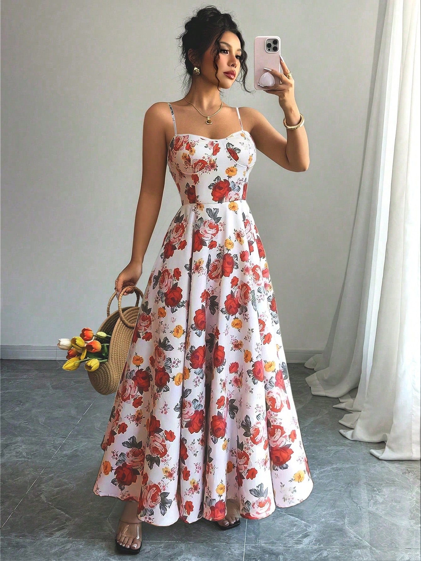 Woman taking a mirror selfie wearing a floral dress in a room with a gray floor and white curtains.