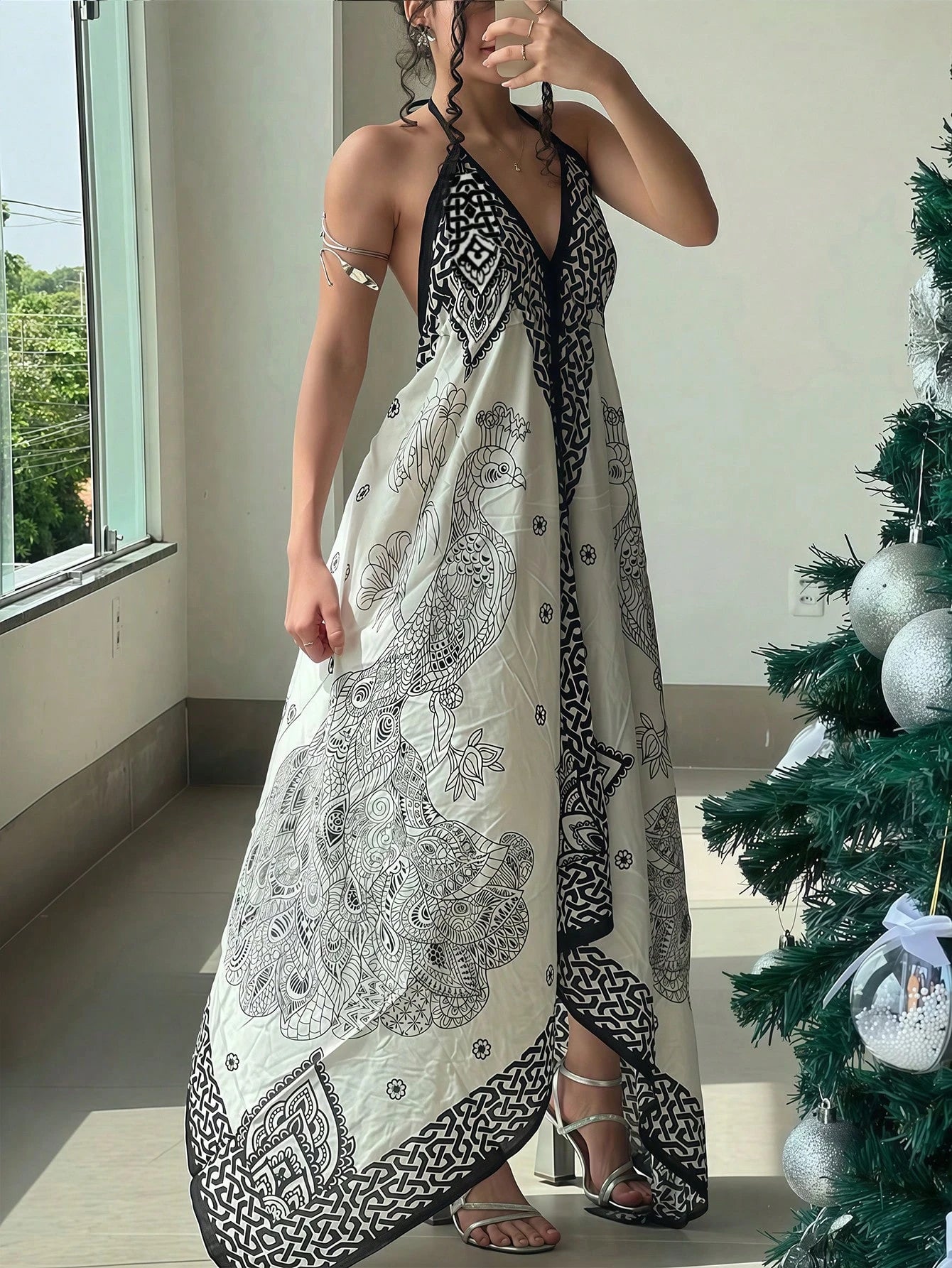 Woman wearing a black and white patterned dress standing next to a decorated Christmas tree.