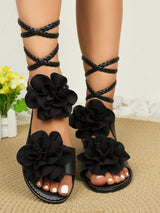Black floral sandals on feet with a neutral background