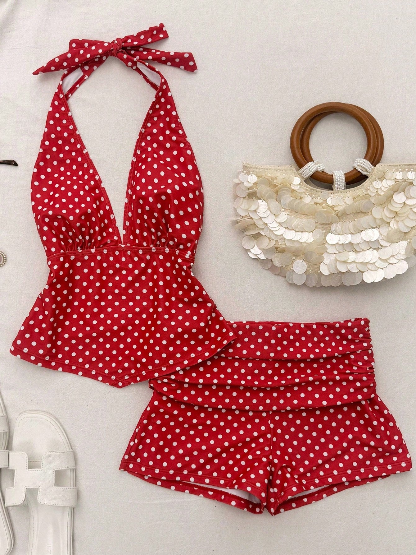 Red polka dot swimsuit with white polka dot shorts and a sequined bag on a light background