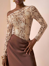 Woman wearing a snake print top and brown skirt against a beige background