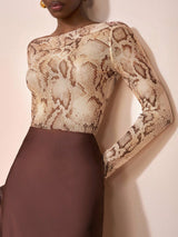 Snakeskin-patterned top worn by a person on a plain background