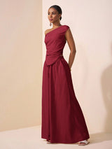 Woman wearing a burgundy one-shoulder dress against a beige background