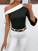 Woman wearing a black and white off-shoulder top with white pants against a white background