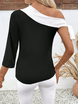 Woman wearing a black and white off-shoulder top with a blurred background