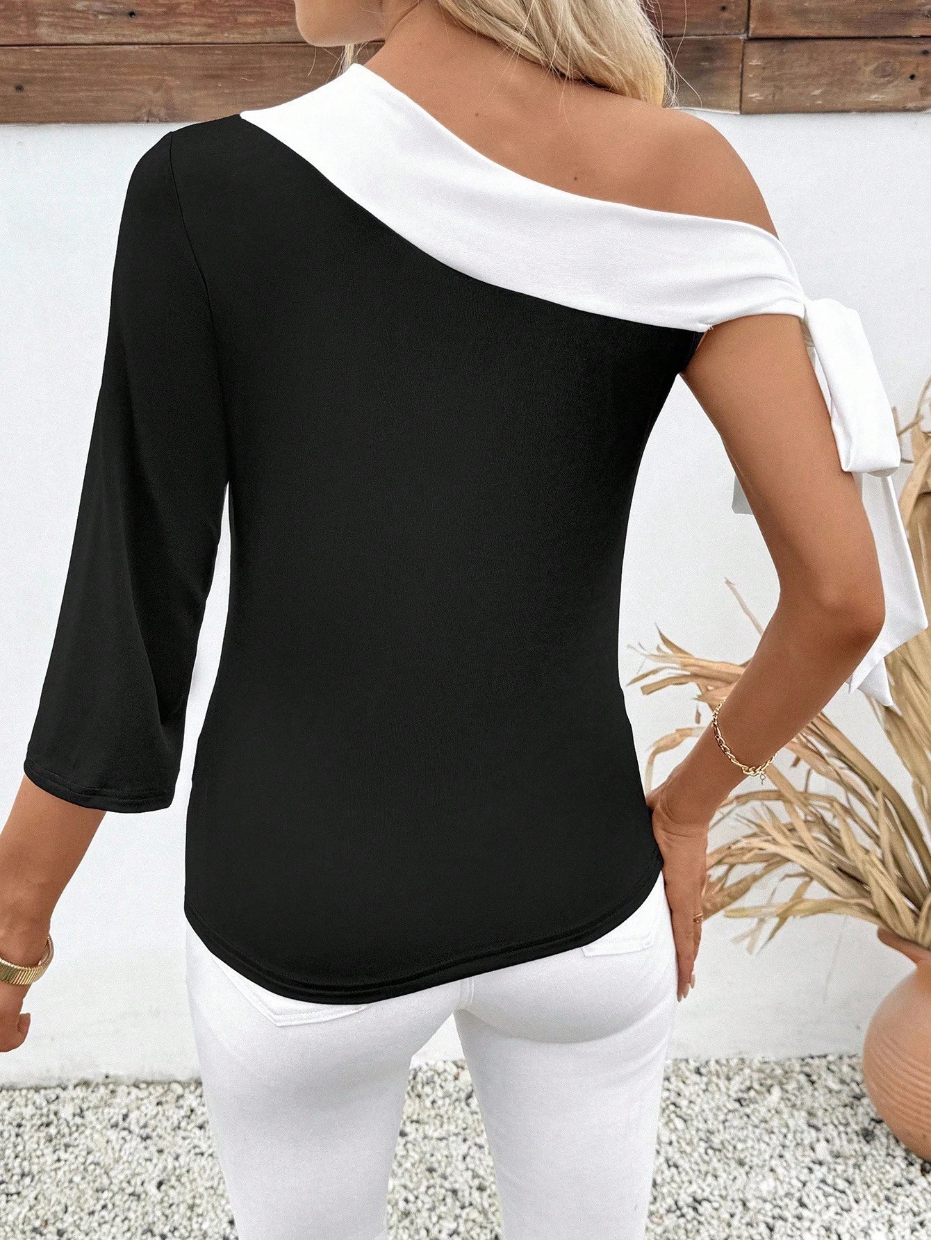Woman wearing a black and white off-shoulder top with a blurred background