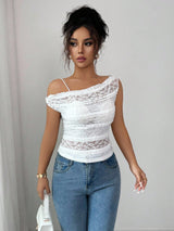Woman wearing a white lace top and blue jeans against a plain background