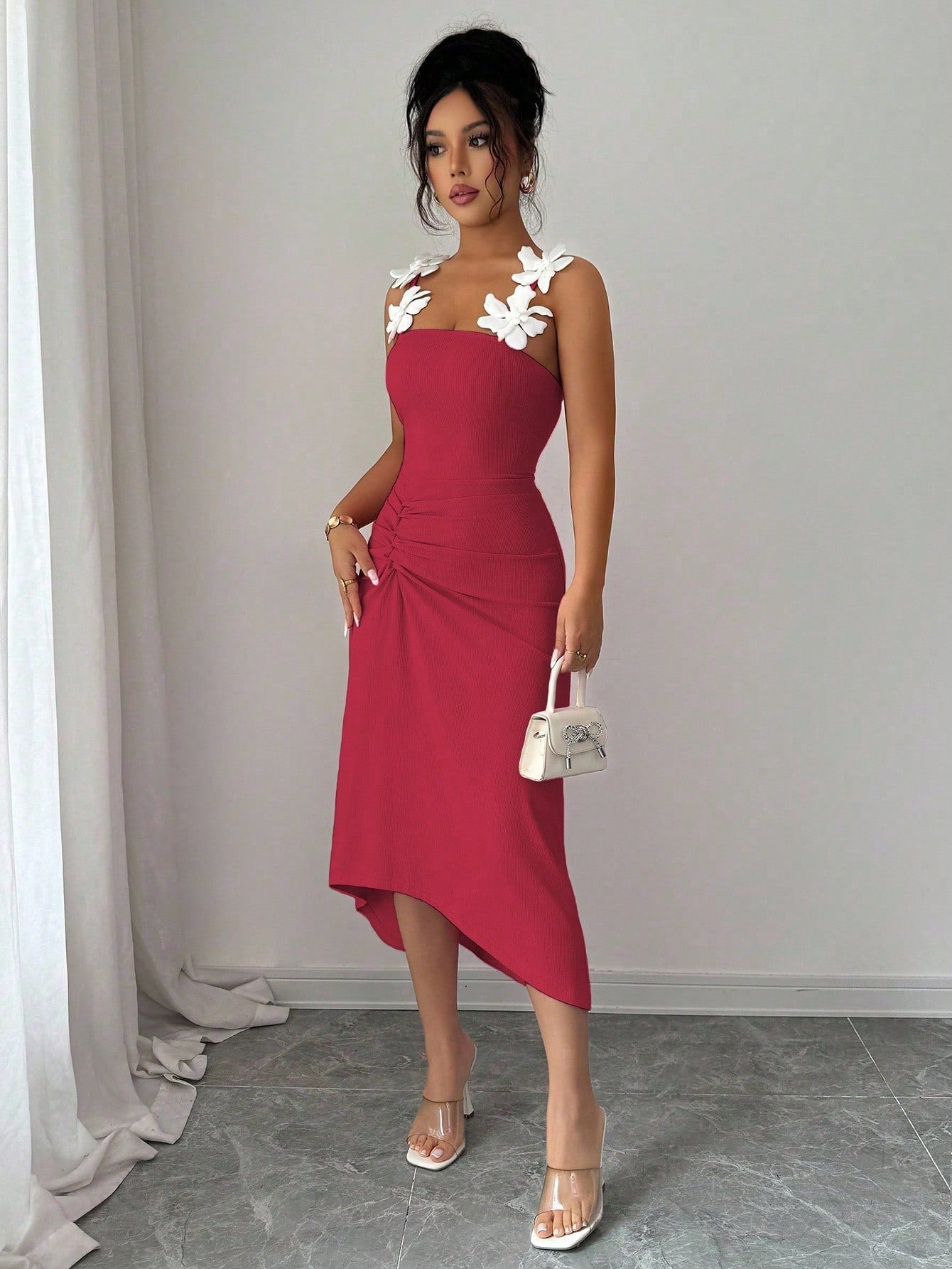 Woman wearing a red dress with floral straps against a plain background