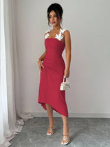 Woman wearing a red dress with floral straps against a plain background