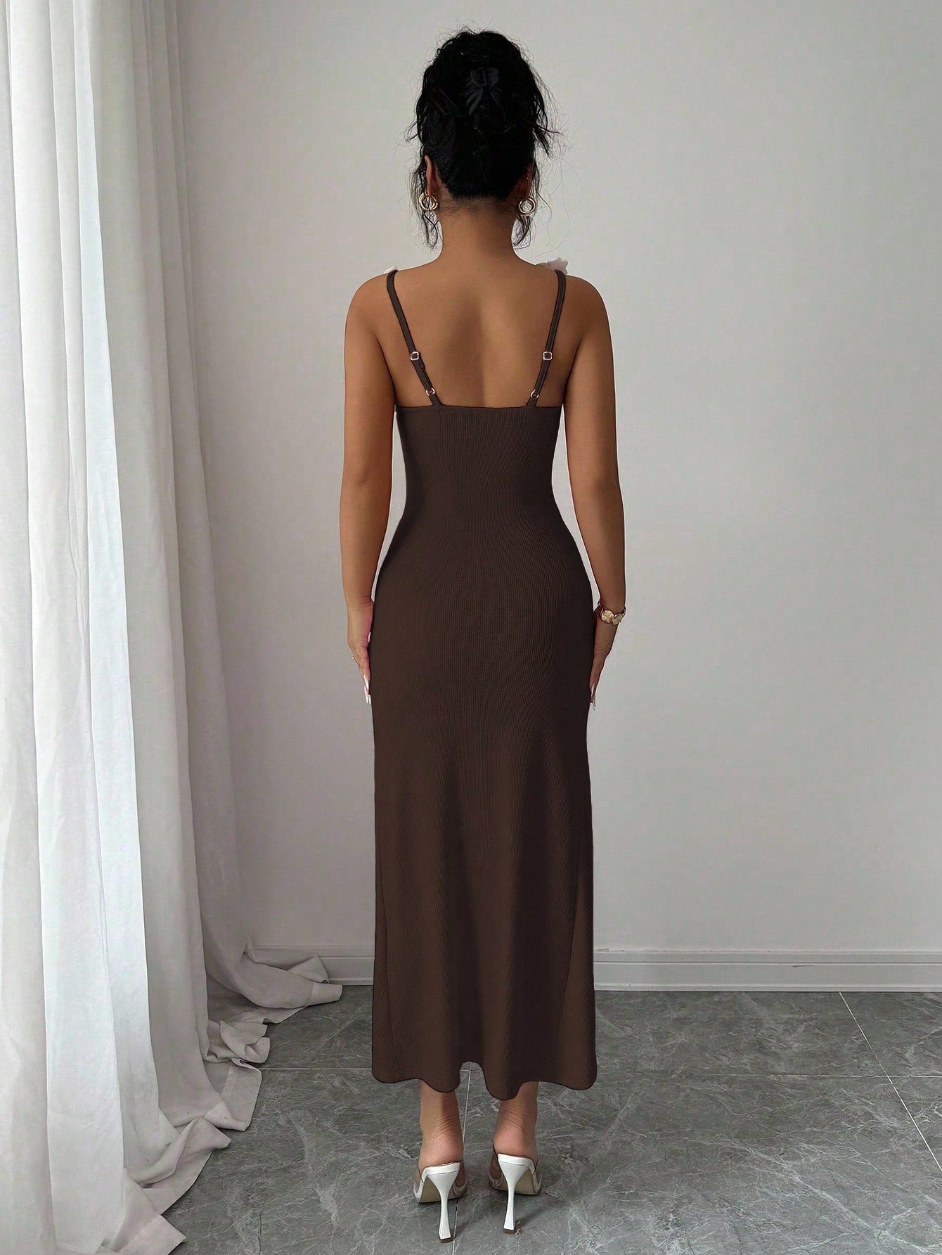 Woman wearing a red slip dress standing against a plain wall.