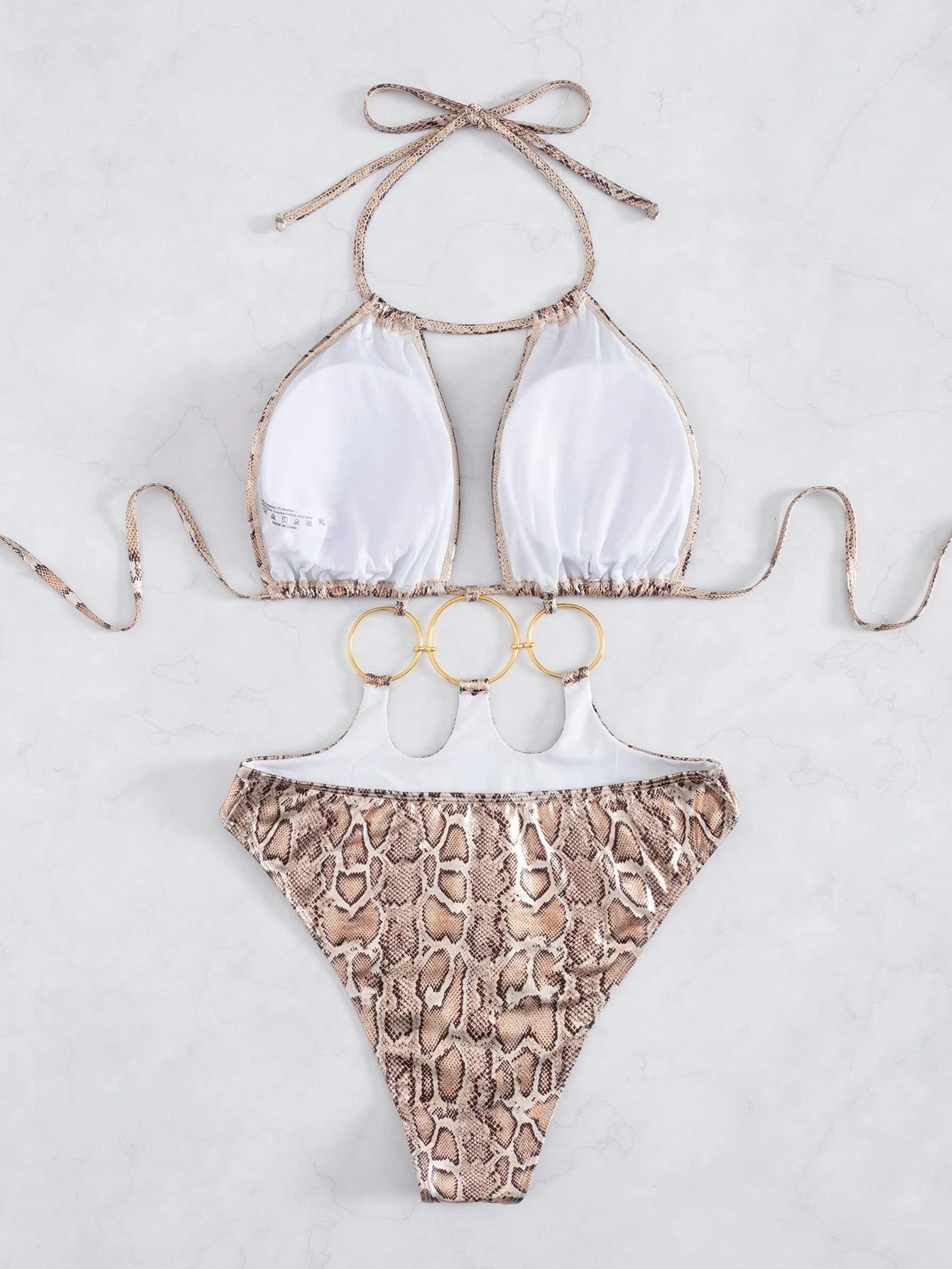 Bikini set with white top and snake print bottom on a light gray background