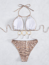 Bikini set with white top and snake print bottom on a light gray background