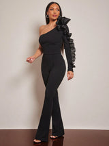 Woman wearing a black one-shoulder jumpsuit with ruffled sleeves against a plain background