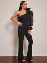 Woman wearing a black one-shoulder jumpsuit with a textured sleeve against a neutral background