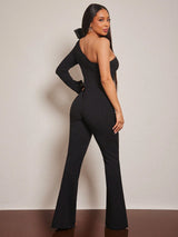 Woman wearing a black jumpsuit against a plain background